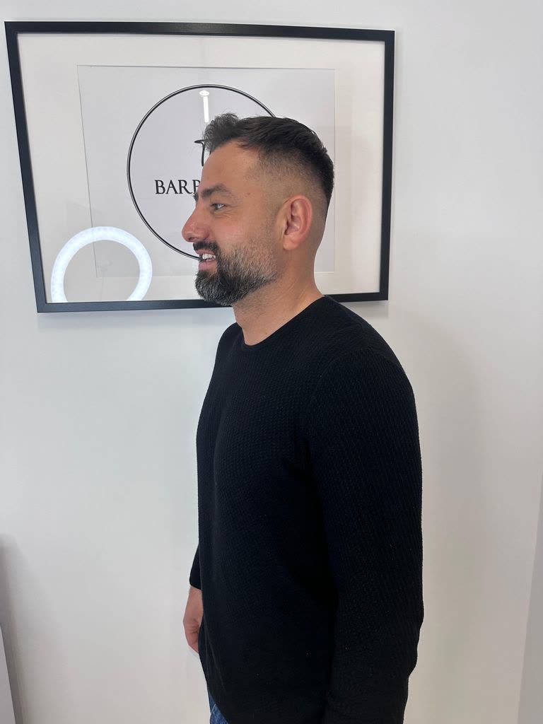Fade scurt cu barbă, din profil, sigla în spate