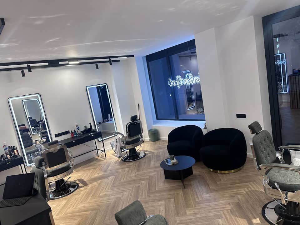Interiorul salonului: oglinzi cu LED, fotolii negre rotunde și firma luminoasă din vitrină